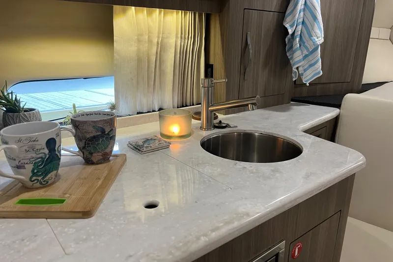Slide: The Image of 2019 Regal 33 Express yacht interior with modern kitchenette, sink, and cozy decor. - 35