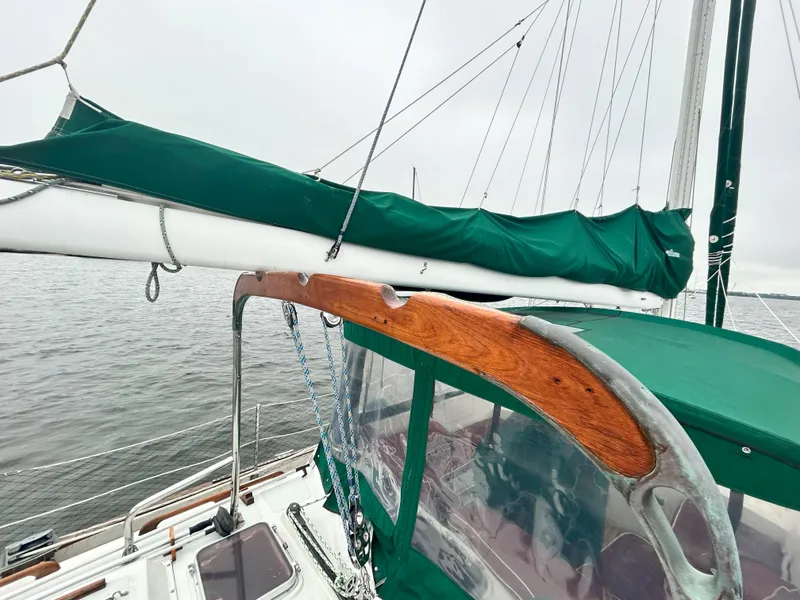 Slide: The Image of Sailboat deck with green sail cover, Passport 51 model, 1987, on calm water. - 21