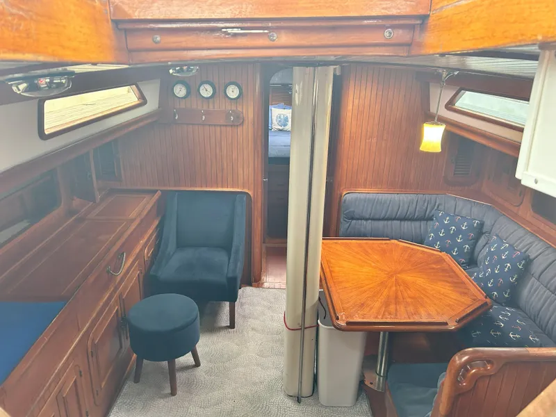 Slide: The Image of Cozy 1987 Passport 51 yacht interior with wood paneling, seating, and nautical-themed cushions. - 30