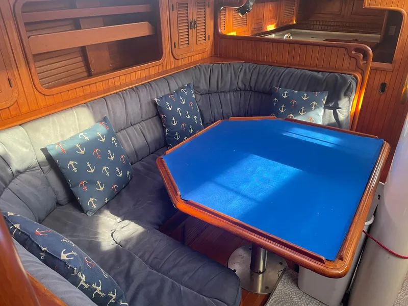 Slide: The Image of Cozy 1987 Passport 51 yacht interior with blue cushioned seating and anchor-themed pillows. - 31