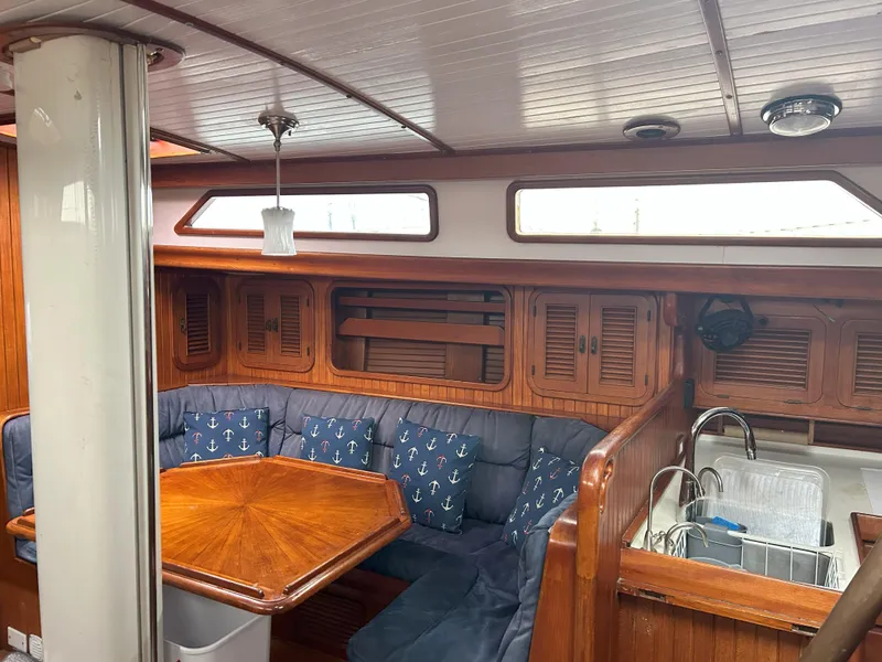 Slide: The Image of 1987 Passport 51 yacht interior with wooden dining area and nautical-themed cushions. - 32