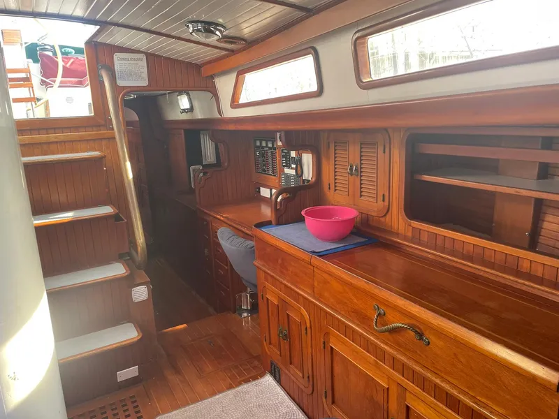 Slide: The Image of Interior of a 1987 Passport 51 sailboat with wooden cabinetry and a pink bowl. - 34