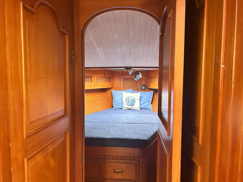 Slide: The Image of Cozy wooden cabin interior on a 1987 Passport 51 yacht, featuring a neatly made bed. - 42