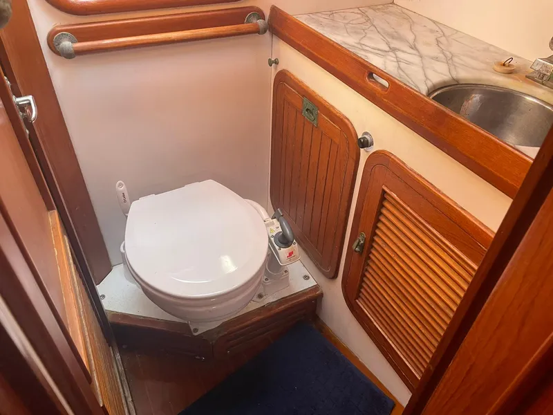 Slide: The Image of Compact boat bathroom with wooden cabinets, marble countertop, and a toilet. Passport 51, 1987 model. - 44