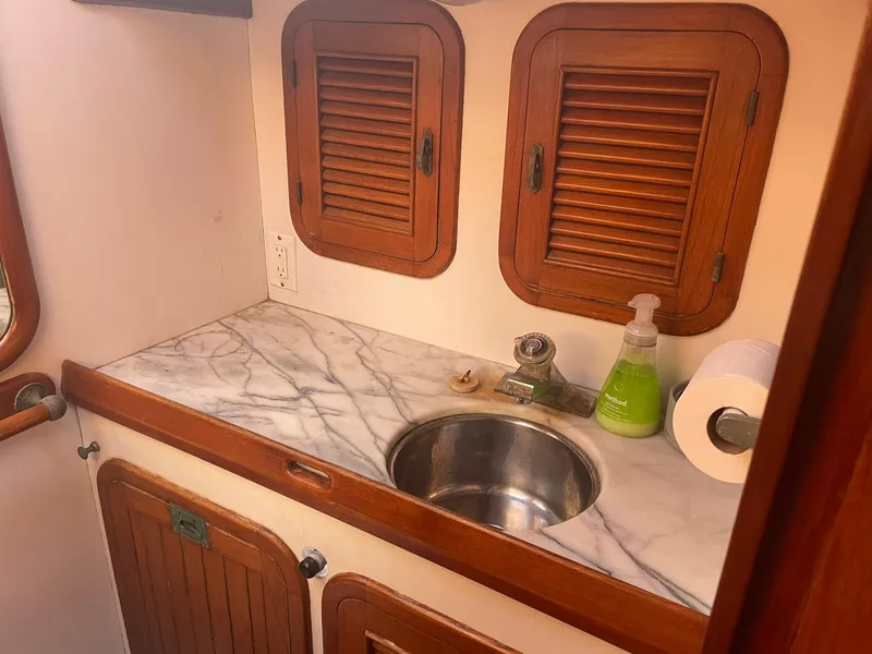 Slide: The Image of 1987 Passport 51 yacht bathroom with marble countertop, stainless steel sink, and wooden cabinets. - 45