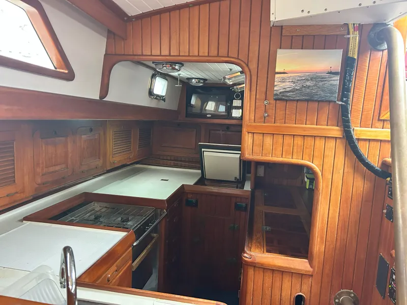 Slide: The Image of 1987 Passport 51 yacht interior with wooden cabinetry and compact kitchen area. - 47