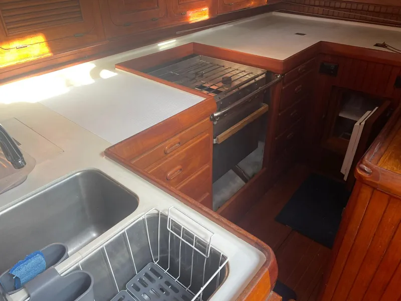 Slide: The Image of 1987 Passport 51 yacht kitchen with wooden cabinetry, stove, and stainless steel sink. - 49
