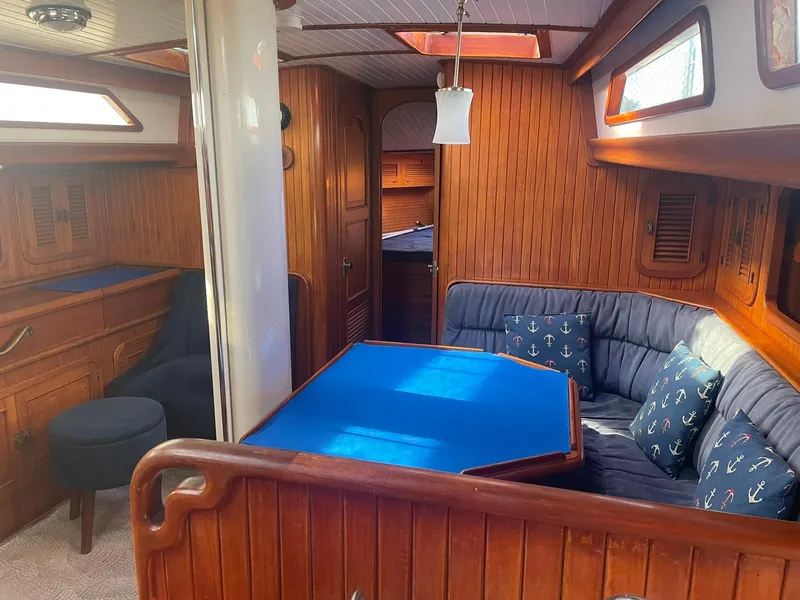 Slide: The Image of Interior of a 1987 Passport 51 yacht with wooden paneling and blue cushioned seating. - 54