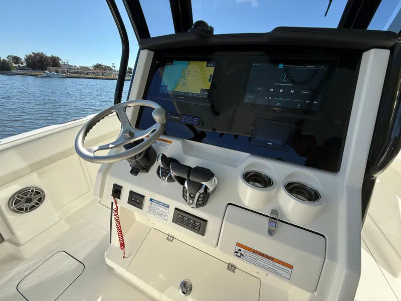 Slide: The Image of 2025 World Cat 280 CC-X boat dashboard with steering wheel and navigation screens. - 11