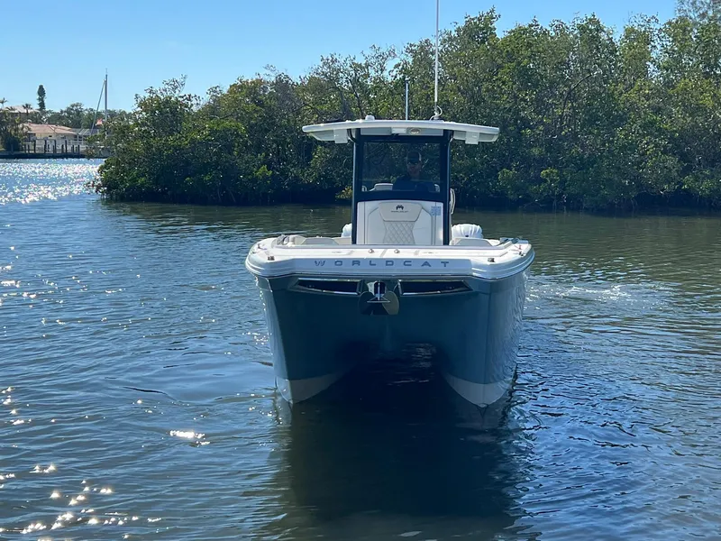 Slide: The Image of 2025 World Cat 280 CC-X boat on calm water near lush greenery. - 2