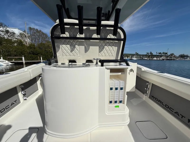 Slide: The Image of 2025 World Cat 280 CC-X boat interior with storage and rod holders, docked by a scenic waterfront. - 9