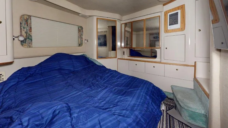 Slide: The Image of 1996 Sea Ray 420 Aft Cabin interior with blue bedding and white cabinetry. - 10