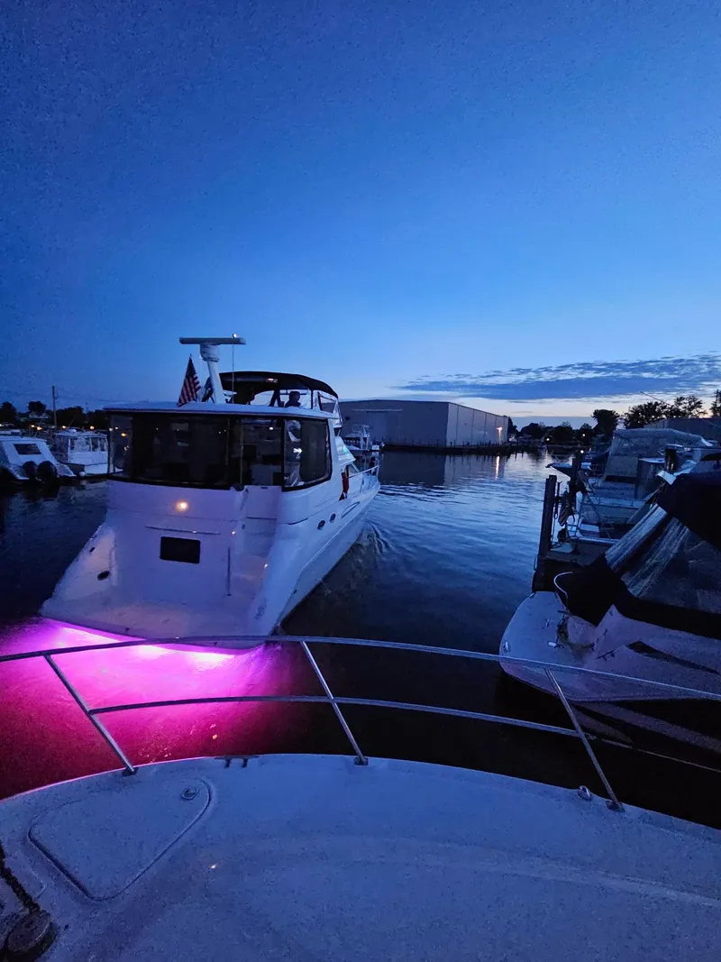 Slide: The Image of 1996 Sea Ray 420 Aft Cabin yacht with purple lights at dusk in a marina. - 15
