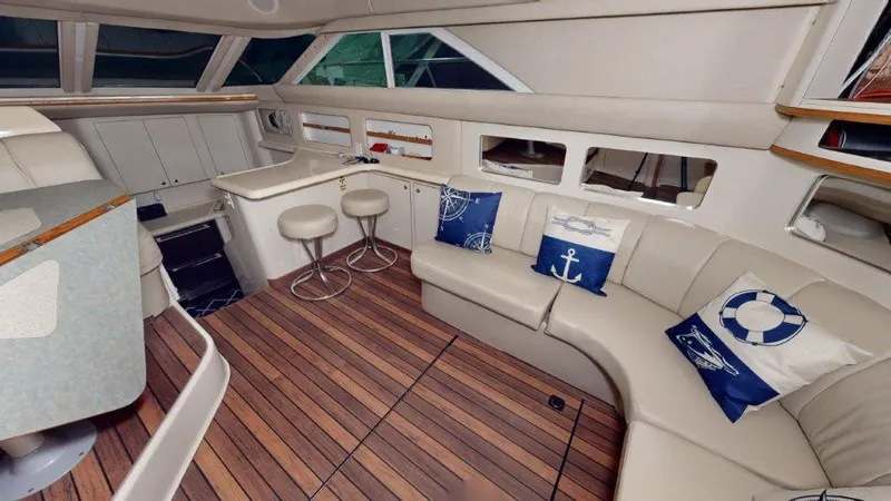 Slide: The Image of 1996 Sea Ray 420 Aft Cabin interior with seating, bar stools, and nautical-themed pillows. - 3