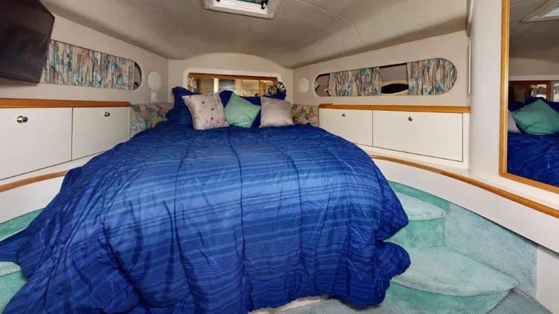 Slide: The Image of Cozy bedroom in 1996 Sea Ray 420 Aft Cabin with blue bedding and decorative pillows. - 8
