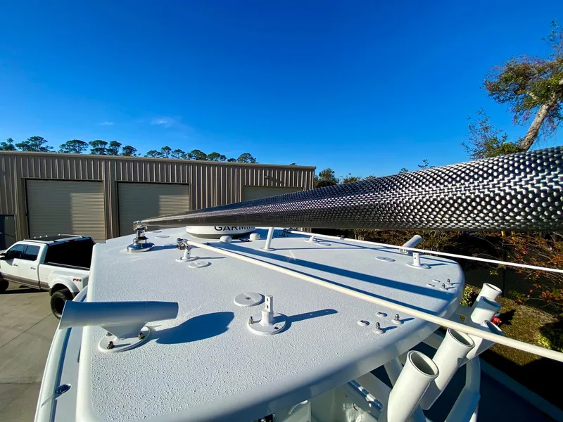Slide: The Image of 2019 Yellowfin 29 Offshore boat with carbon fiber outrigger, parked near industrial buildings. - 15