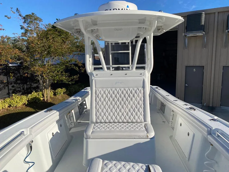 Slide: The Image of 2019 Yellowfin 29 Offshore boat with white seating and canopy, docked near a building. - 18