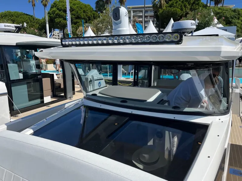 Slide: The Image of 2026 Saxdor 340 GTWA boat interior with white seating and wooden table, docked by water. - 18