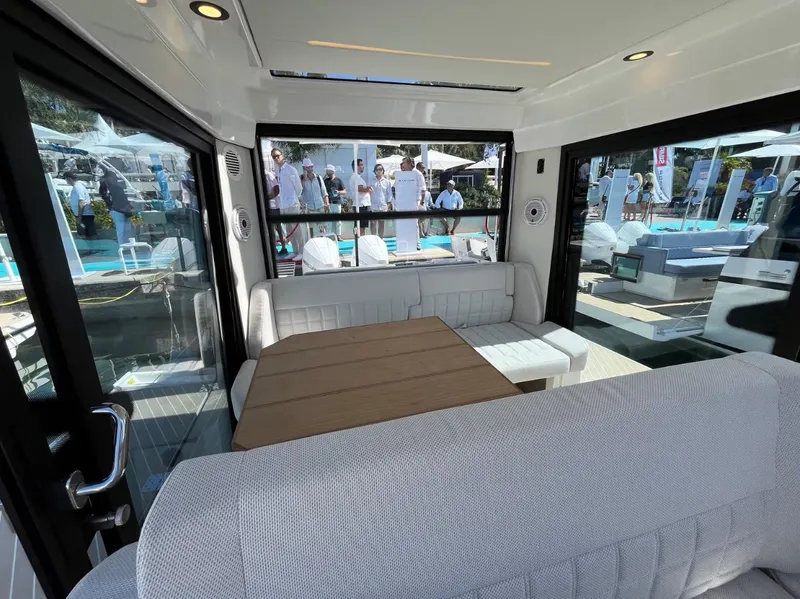 Slide: The Image of 2025 Saxdor 340 GTWA boat interior with seating and table, docked on calm water. - 20