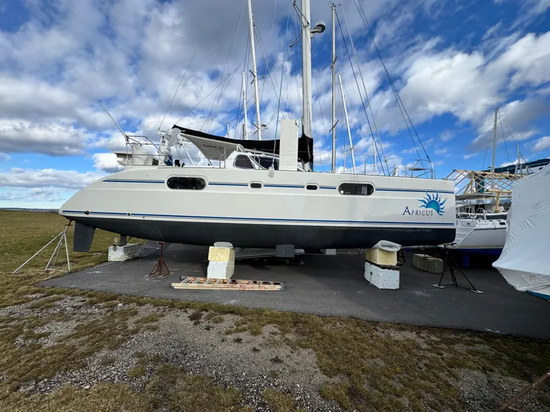 Slide: The Image of 2003 Catana 431 catamaran on land, under a partly cloudy sky. - 1