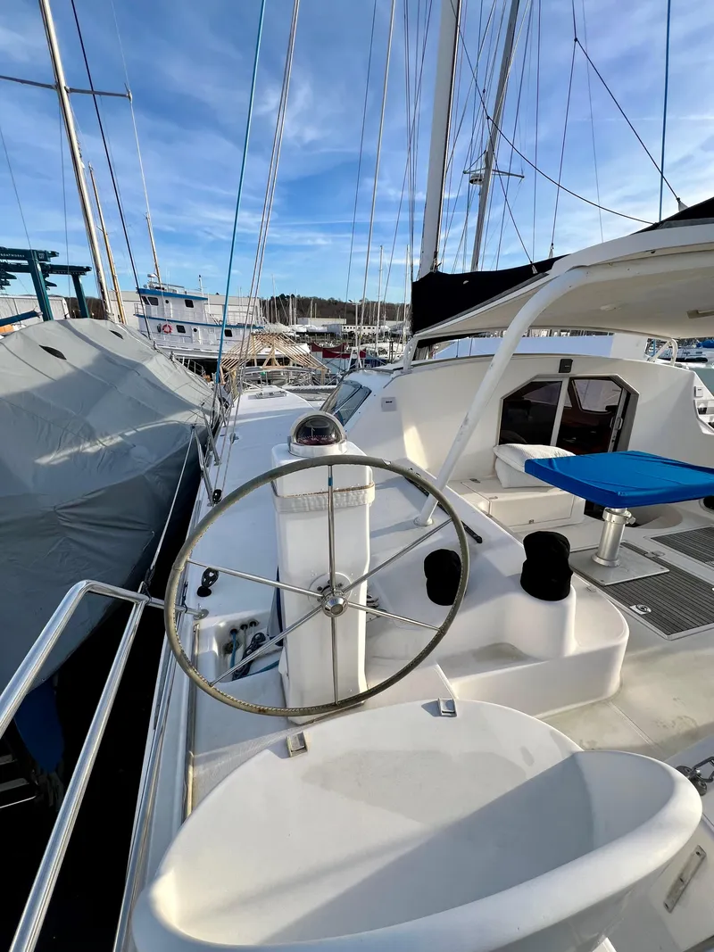 Slide: The Image of 2003 Catana 431 sailboat with steering wheel, docked in marina under blue sky. - 13
