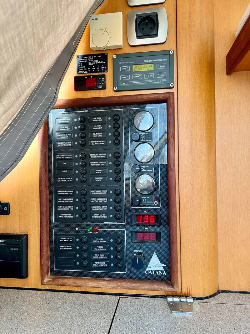Slide: The Image of Control panel of a 2003 Catana 431 yacht, featuring various switches and gauges. - 19