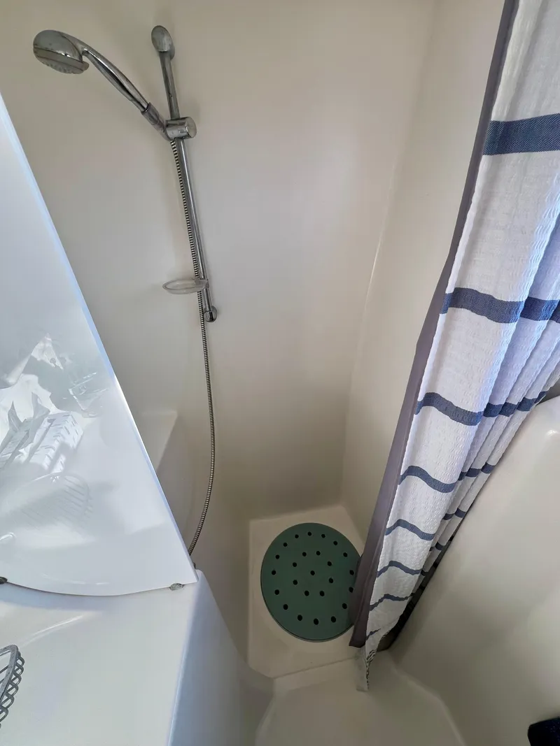 Slide: The Image of Compact shower area in a 2003 Catana 431 yacht with striped curtain and handheld showerhead. - 30