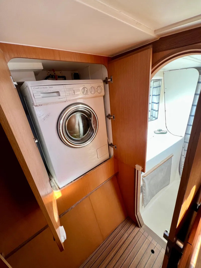 Slide: The Image of Washing machine inside 2003 Catana 431 catamaran, wooden interior, open cabinet door. - 32