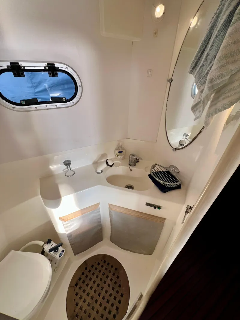 Slide: The Image of Bathroom interior of a 2003 Catana 431 yacht, featuring a sink, toilet, and porthole window. - 33