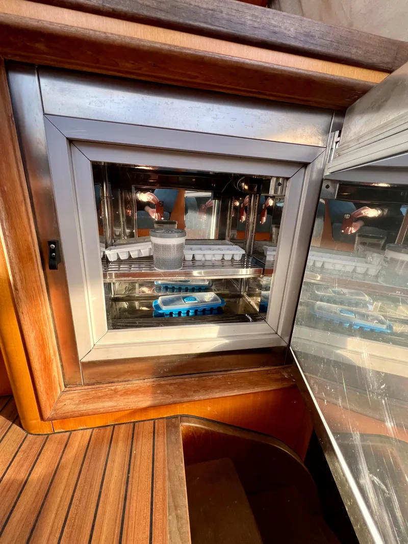 Slide: The Image of Open refrigerator on Catana 431 yacht, showcasing interior storage and wooden cabinetry. - 36