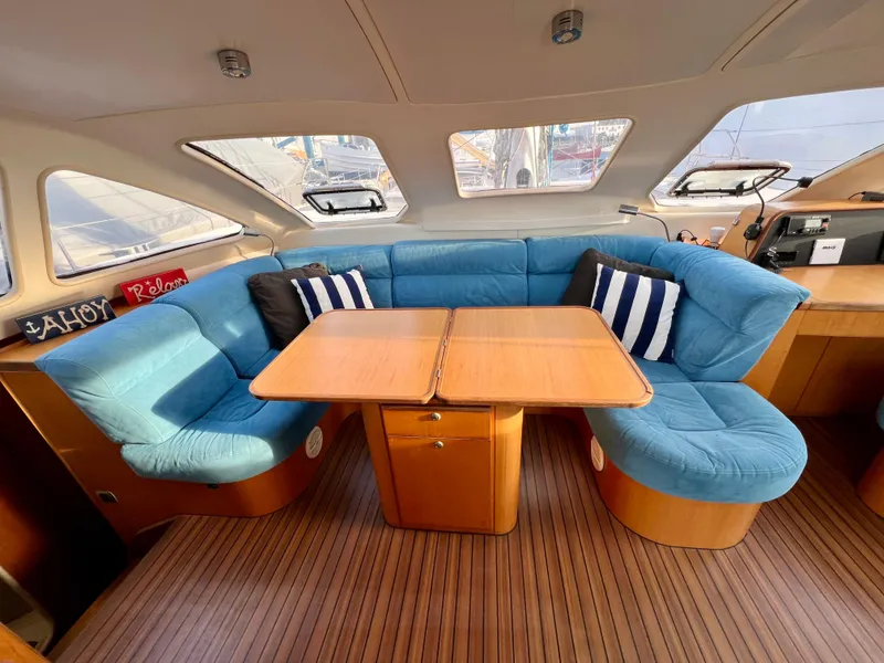 Slide: The Image of Interior of 2003 Catana 431 yacht with blue cushioned seating and wooden table. - 40