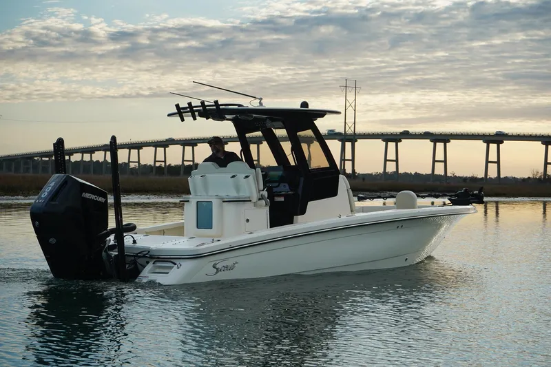 Slide: The Image of 2025 Scout 261 XSS boat cruising on calm water near a bridge at sunset. - 11