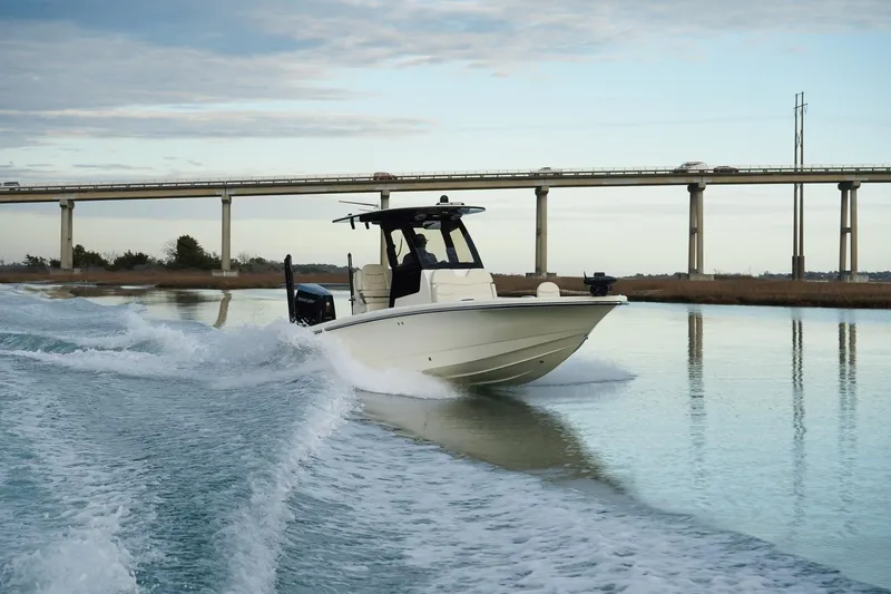 Slide: The Image of 2025 Scout 261 XSS boat cruising on a calm river near a bridge. - 12