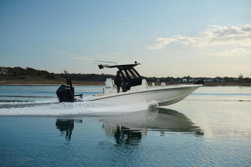 Slide: The Image of 2025 Scout 261 XSS boat cruising on calm water under a clear sky. - 15