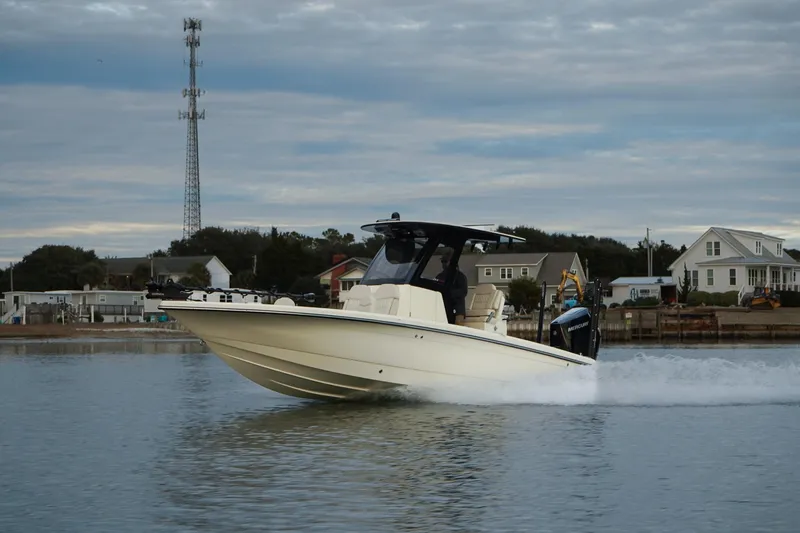 Slide: The Image of 2025 Scout 261 XSS boat cruising on a calm waterway near residential area. - 17