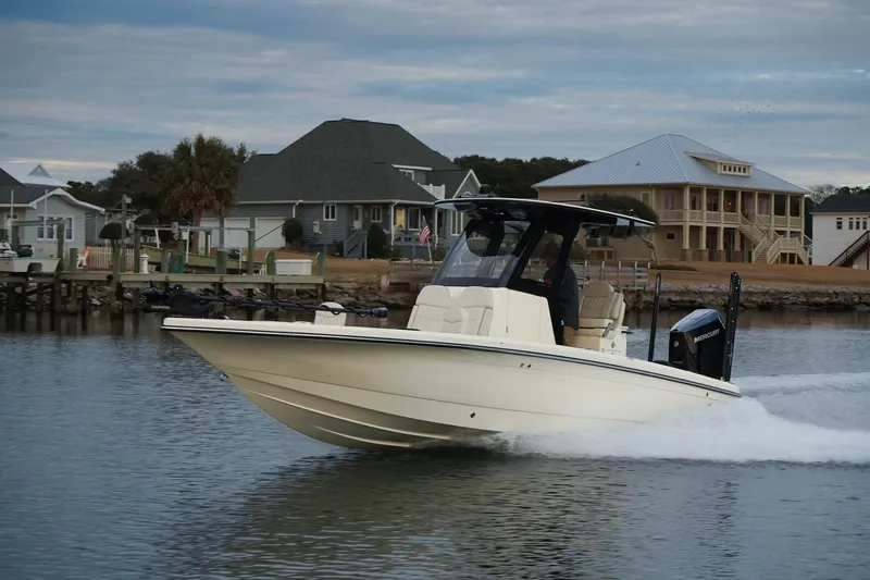 Slide: The Image of 2025 Scout 261 XSS boat cruising on a calm waterfront near residential homes. - 18