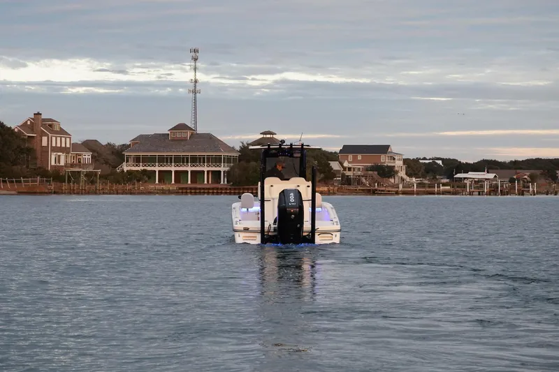 Slide: The Image of 2025 Scout 261 XSS boat cruising near coastal homes under cloudy sky. - 23
