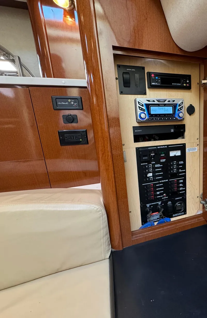Slide: The Image of 2008 Sea Ray 310 Sundancer interior control panel with wood finish and beige seating. - 13