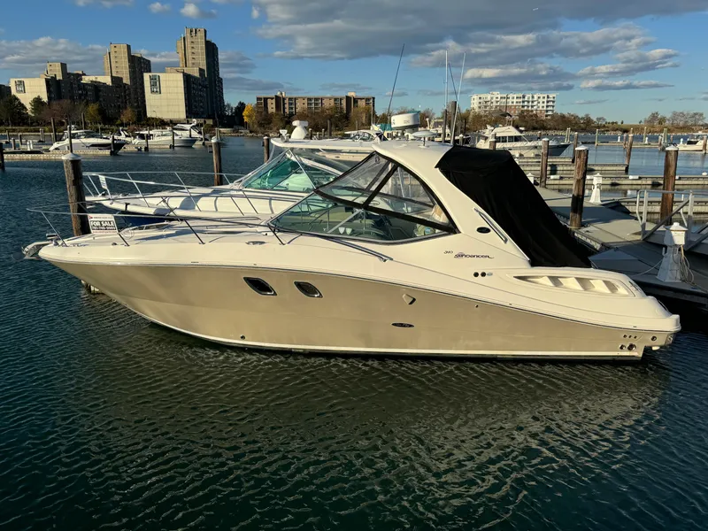 Slide: The Image of 2008 Sea Ray 310 Sundancer docked in a marina with cityscape background. - 2