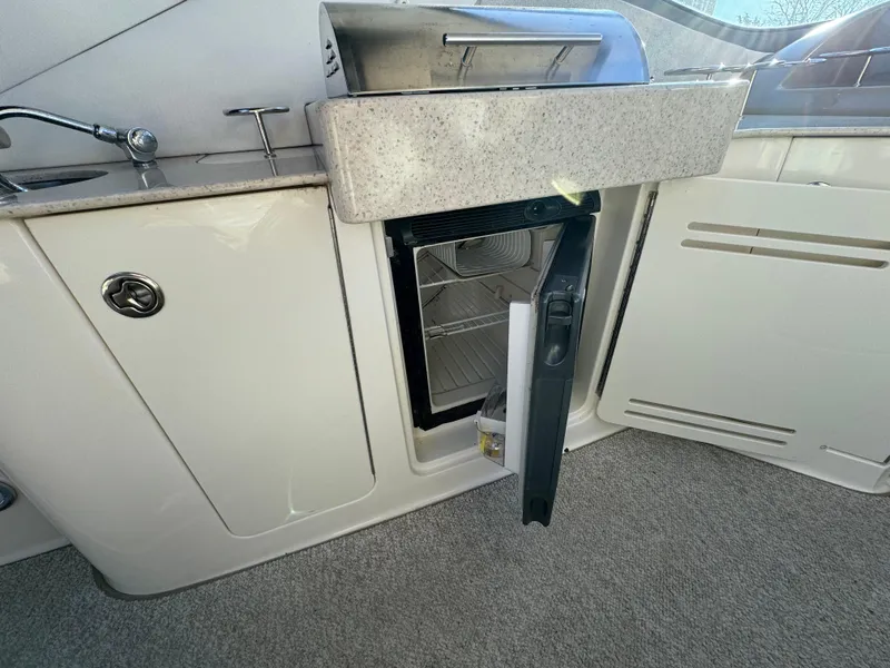 Slide: The Image of 2008 Sea Ray 310 Sundancer interior with open mini fridge and sink. - 22