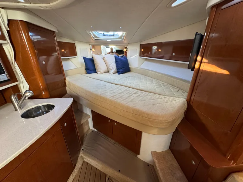 Slide: The Image of 2008 Sea Ray 310 Sundancer cabin with bed, sink, and wooden cabinetry. - 8