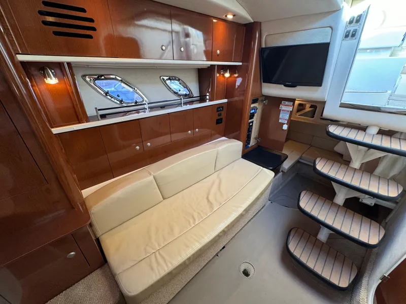 Slide: The Image of 2008 Sea Ray 310 Sundancer interior with beige sofa, wooden cabinetry, and modern staircase. - 9