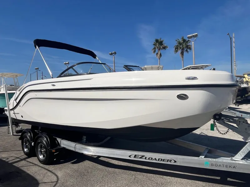 Slide: The Image of 2021 Bayliner DX 2200 boat on trailer, displayed outdoors under clear blue sky. - 1