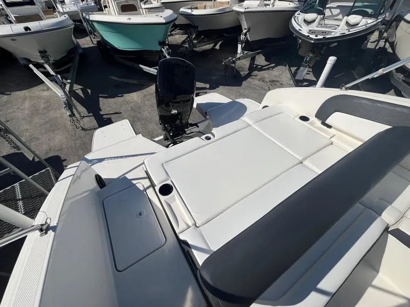 Slide: The Image of 2021 Bayliner DX 2200 boat with spacious seating and outboard motor in a marina. - 12