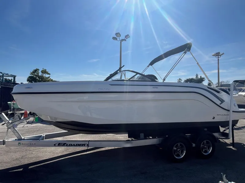 Slide: The Image of 2021 Bayliner DX 2200 boat on trailer under bright sunlight. - 3