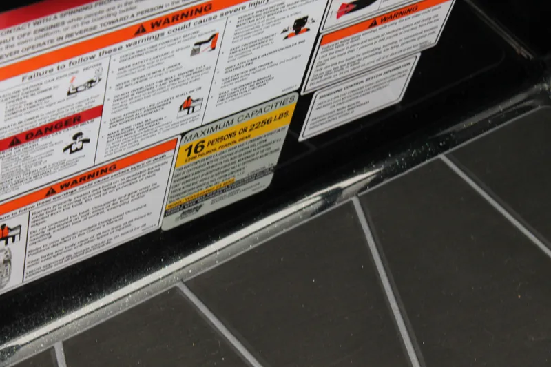 Slide: The Image of Warning labels on 2025 Malibu 23 MXZ boat, showing maximum capacity and safety instructions. - 10