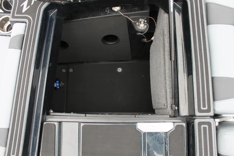 Slide: The Image of Open storage compartment in 2025 Malibu 23 MXZ boat, featuring sleek black interior design. - 11