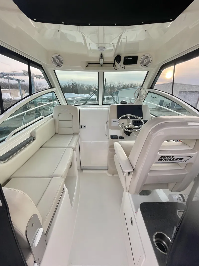 Slide: The Image of 2022 Boston Whaler 285 Conquest interior with helm, seating, and panoramic windows. - 12