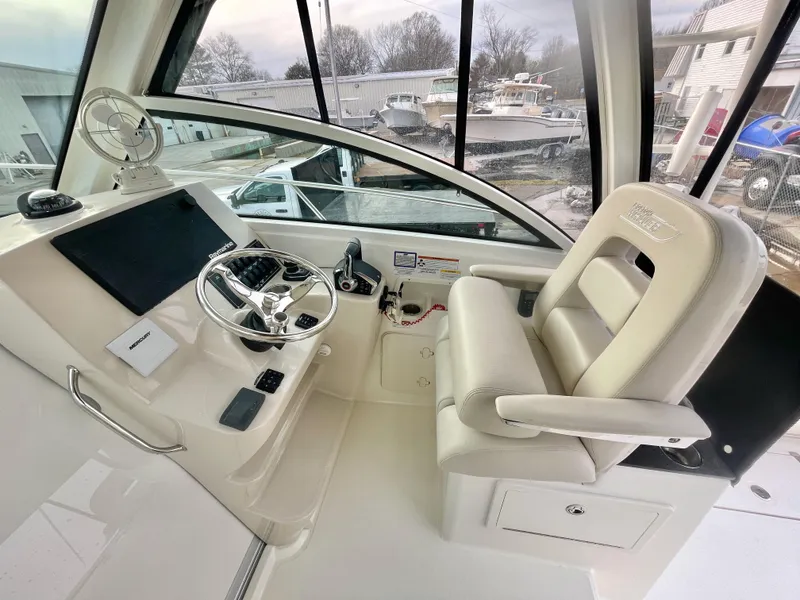 Slide: The Image of 2022 Boston Whaler 285 Conquest helm with steering wheel and captain's chair. - 13