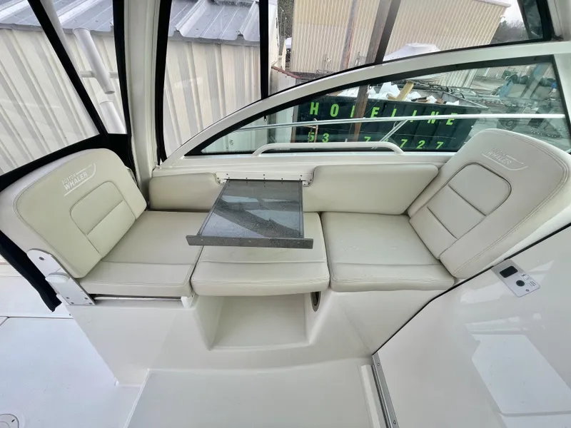 Slide: The Image of 2022 Boston Whaler 285 Conquest interior seating with table, showcasing luxury and comfort. - 16